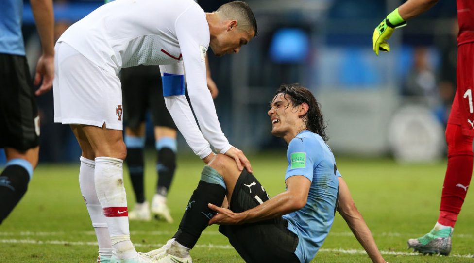 SOCHI, RUSSIA - JUNE 30:  Cristiano Ronaldo of Portugal helps Edinson Cavani of Uruguay after he goes down injured during the 2018 FIFA World Cup Russia Round of 16 match between Uruguay and Portugal at Fisht Stadium on June 30, 2018 in Sochi, Russia.  (Photo by Alex Livesey/Getty Images)