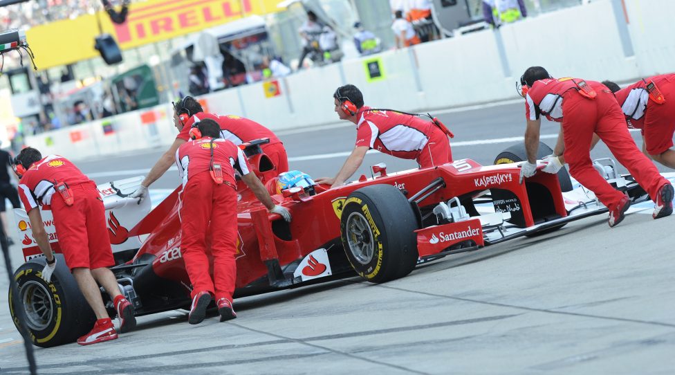 Mechanics push the machine of Ferrari driver Fernando Alonso of Spain to his pit during the second free practice session of the Formula One Japanese Grand Prix in the Suzuka circuit on October 5, 2012.     AFP PHOTO/Toru YAMANAKA        (Photo credit should read TORU YAMANAKA/AFP/GettyImages)